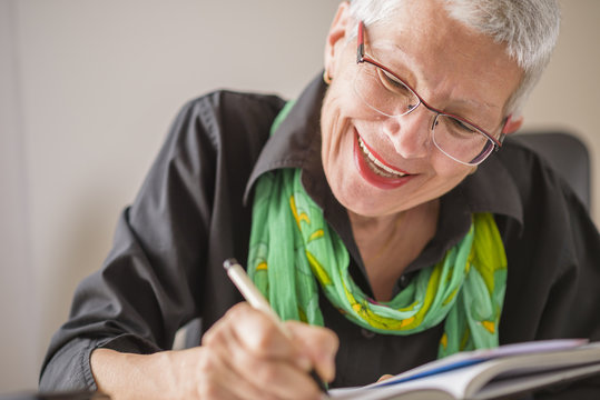 Senior old woman writing down letters on a piece of paper, recording a  journal or diary entry or writing a novel Stock Photo | Adobe Stock